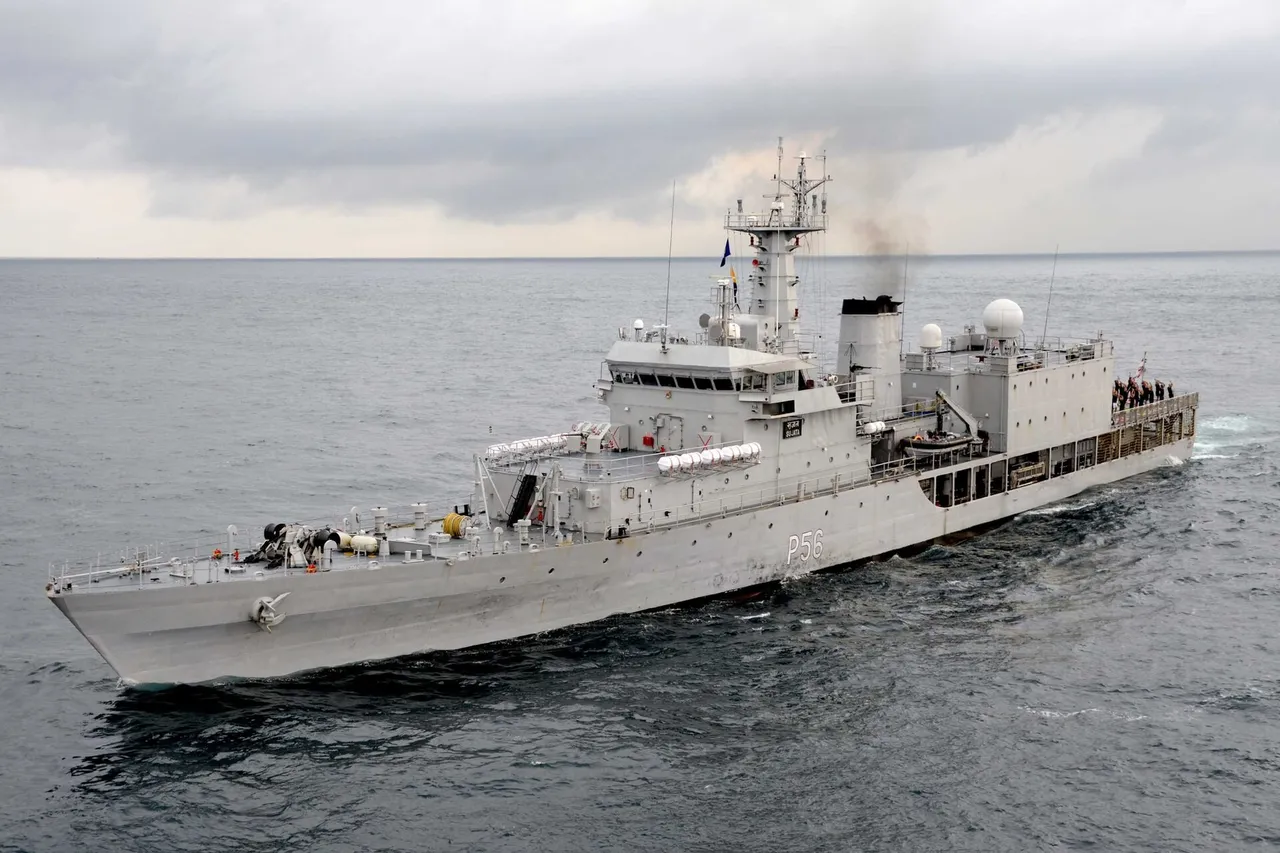 A grey Indian Navy patrol ship with the pennant number P56 sails through a calm grey sea under a cloudy sky, with crew members gathered on its stern deck