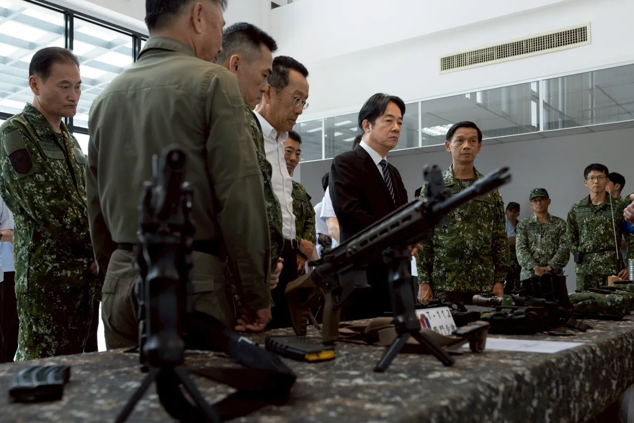 Soldiers in camouflage uniforms stand around a table displaying rifles and a machine gun while a man in a dark suit looks on.