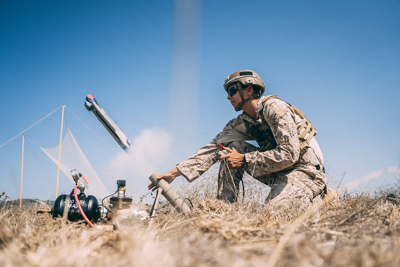 A US Marine kneels in dry grass beside a launch tube as a small Switchblade drone flies out of it against a blue sky