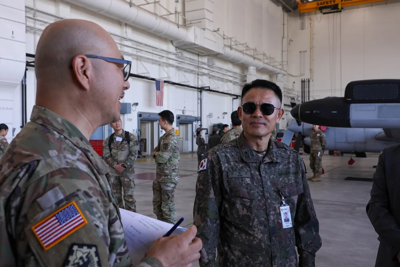 A US Army soldier holding papers talks with a South Korean Army general in a hangar at Camp Humphreys