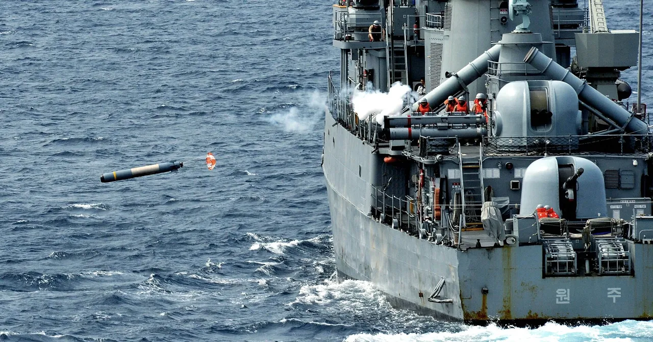 A grey warship launches a torpedo from a deck-mounted tube into the sea, with smoke rising from the launcher