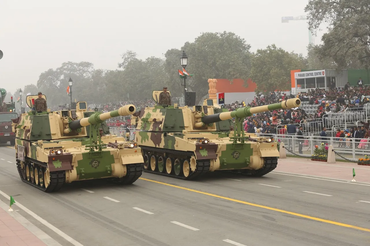 Tracked self-propelled howitzers with long gun barrels drive in a column along a parade avenue