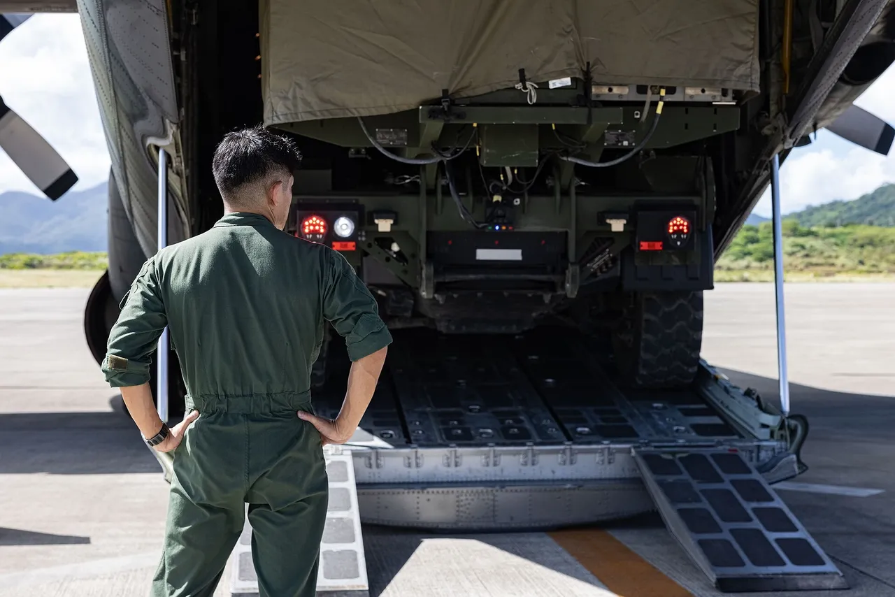 A military vehicle carrying a missile launcher is driven down the rear ramp of a transport aircraft on an airfield