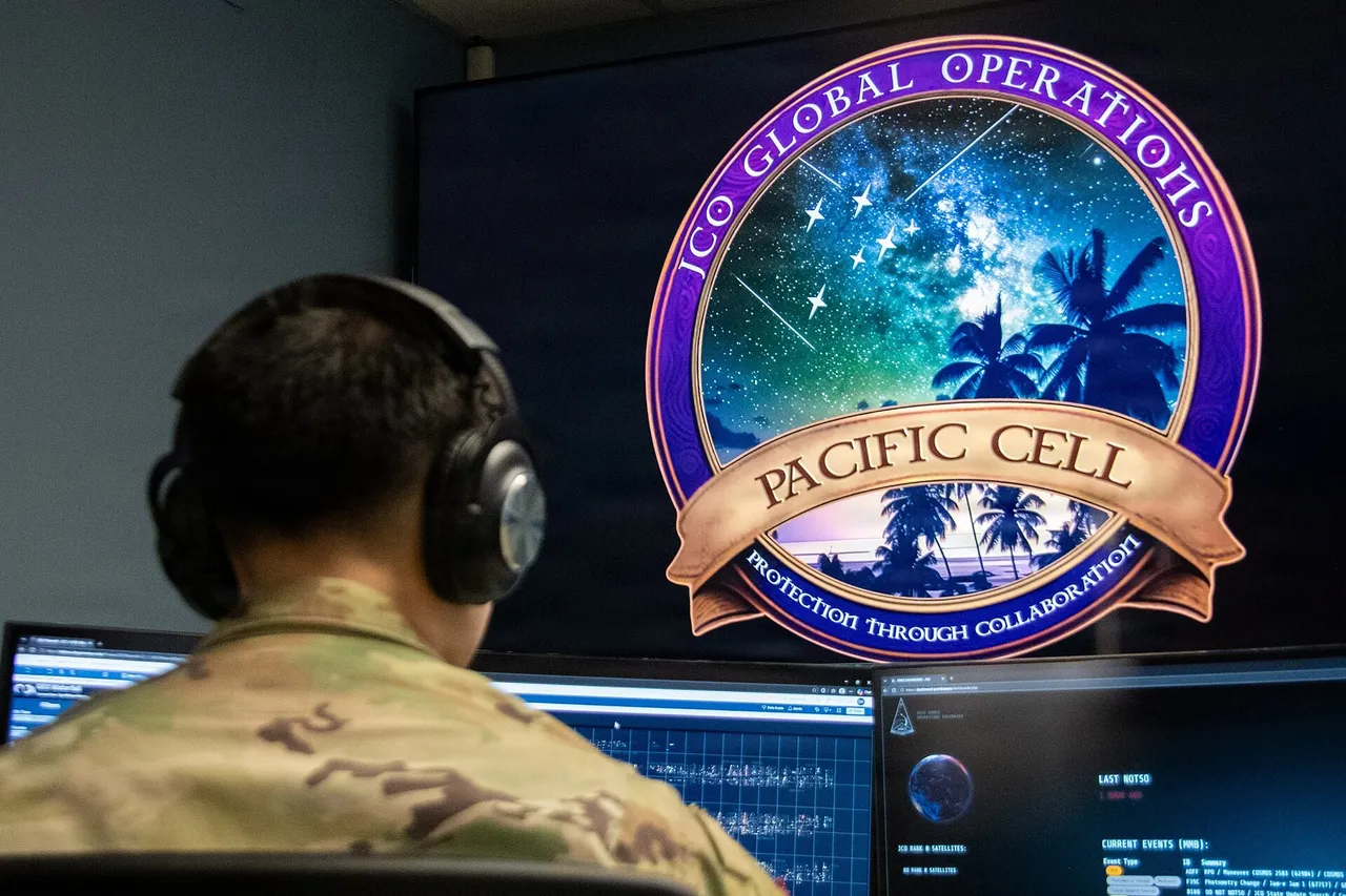 A uniformed airman sits at a desk with several monitors showing satellite tracking data
