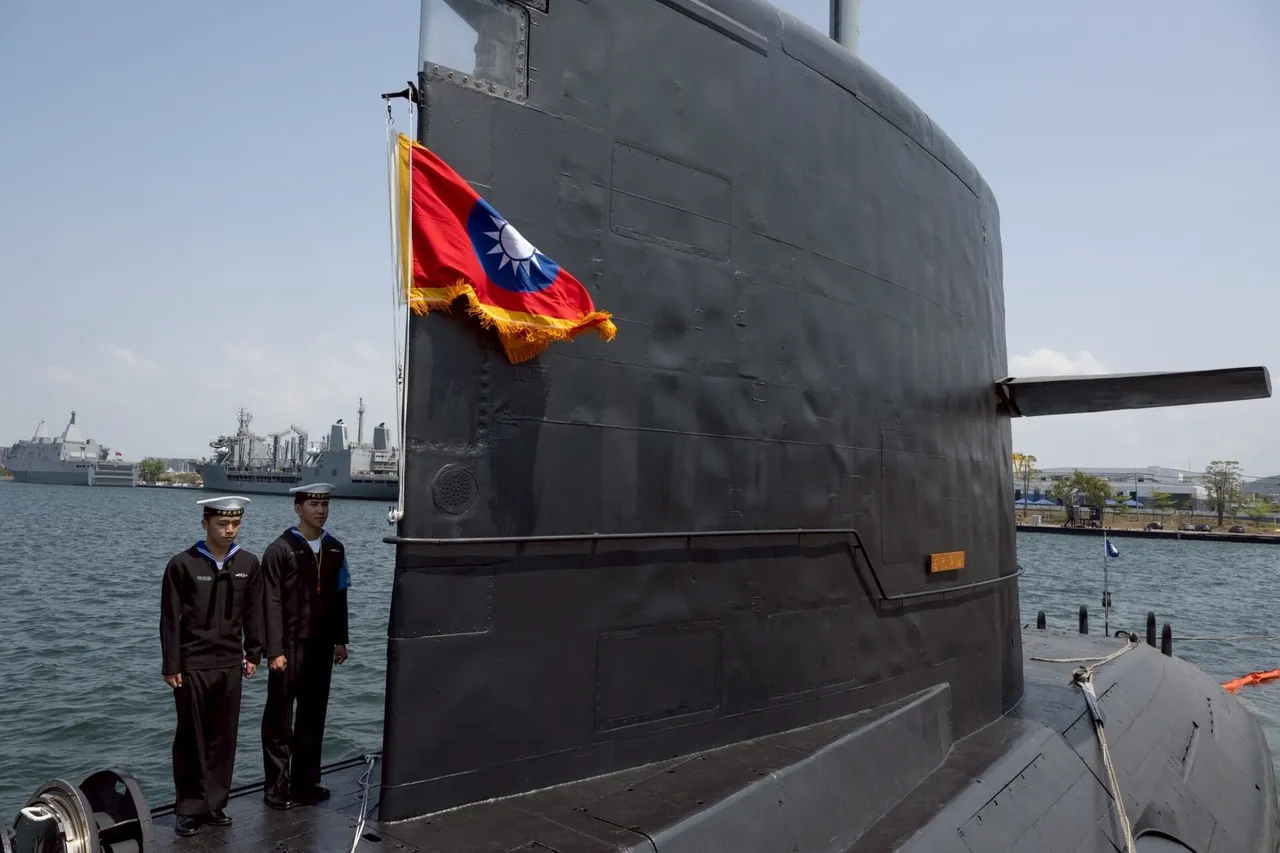 Two Taiwanese sailors in dark uniforms stand on the deck beside the black sail of a submarine flying the Republic of China flag in a harbour