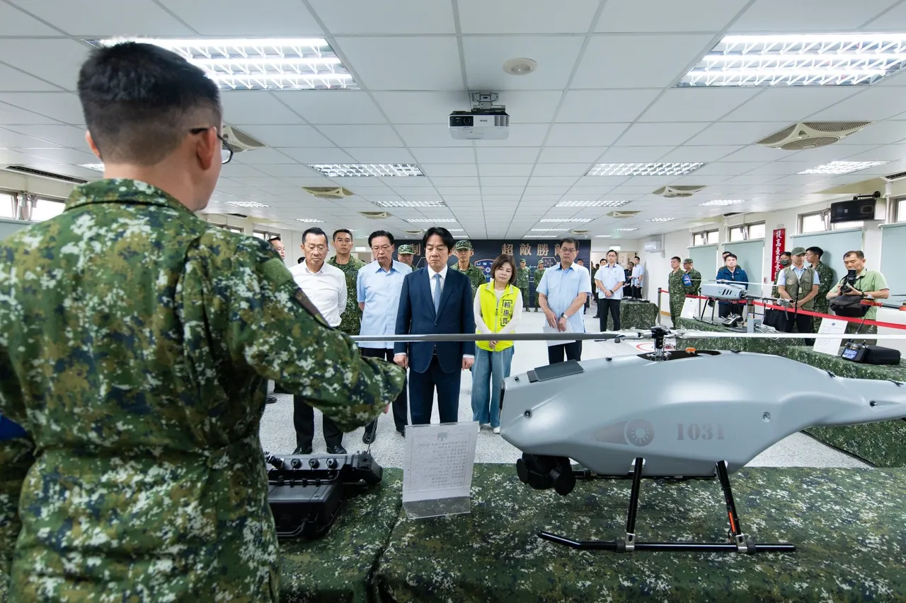 A Taiwanese army officer in camouflage stands beside a grey unmanned helicopter while officials in suits look on inside a hall