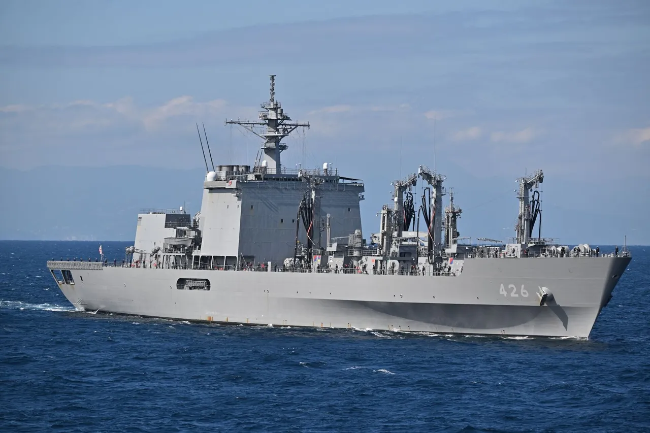 A large grey Japanese navy replenishment ship with hull number 426 and tall refuelling rigs sails across blue sea