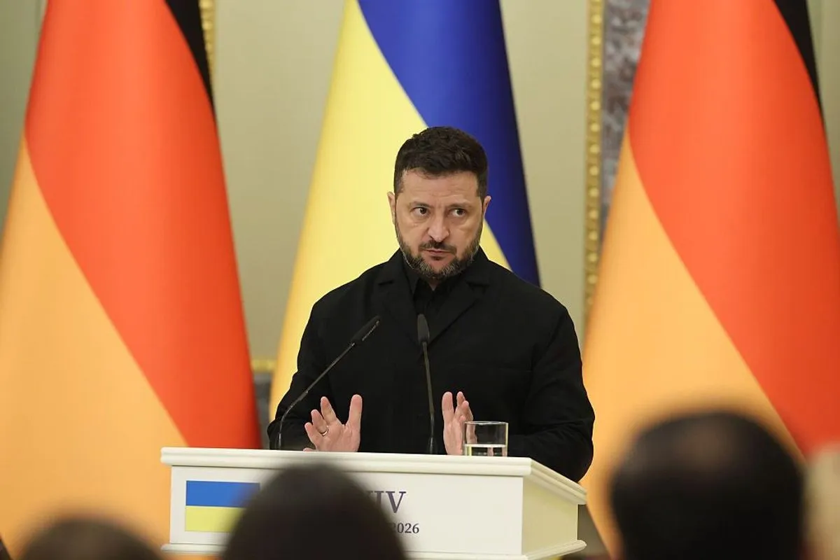 Volodymyr Zelensky in a black jacket speaks at a podium in front of Ukrainian and German flags