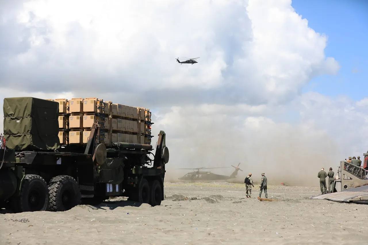 A US Army Patriot missile launcher truck drives off a hovercraft onto a beach