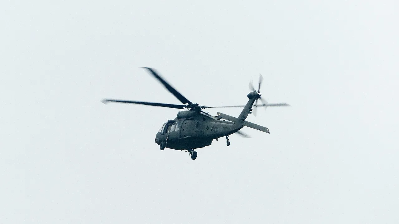 A dark green military Black Hawk helicopter flying against a pale grey sky.