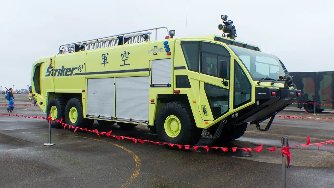 A large red airport crash rescue fire truck with a roof-mounted water cannon parked on an air base apron